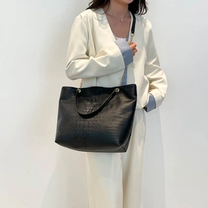 Large black crocodile pattern tote bag with gold chain strap shown on model for office wear