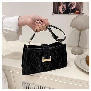 Detail of black crinkled leather handbag with elegant gold buckle and shoulder strap