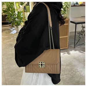 Close-up of brown quilted leather crossbody bag with vintage gold buckle and chain strap