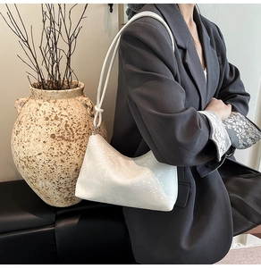 Detail of white faux snakeskin texture and knot strap on a crescent underarm bag