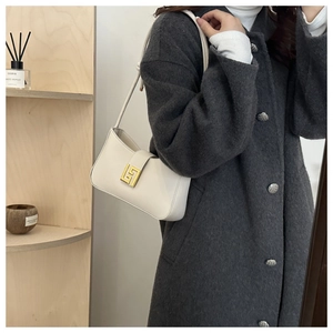 Detail of white leather shoulder bag with gold square buckle styled on a wool coat