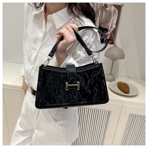 Detail of black pleated baguette bag showing golden buckle and textured leather finish