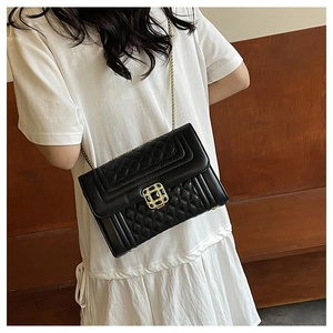 Detail of black quilted leather crossbody bag with gold chain strap and metal buckle