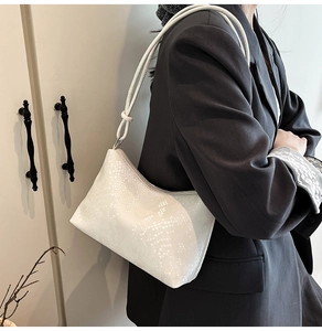Detail of white faux snake pattern shoulder bag with a unique circular drawstring knot strap