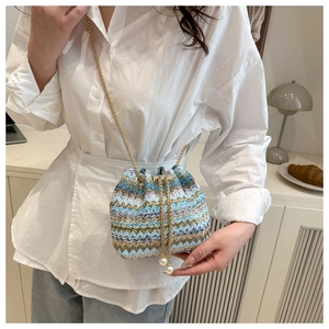 Close-up of colorful woven bucket bag with golden chain and pearl drawstring charms