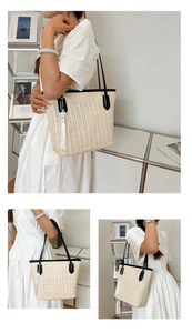 Close-up of woven straw tote bag featuring contrast leather trim and white tassel detail