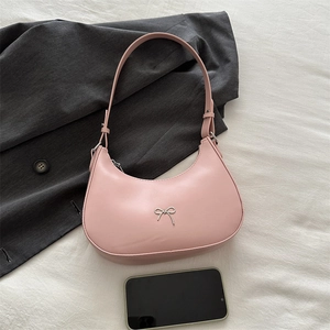 Detail of pink crescent bag with silver bow buckle next to a smartphone for size reference