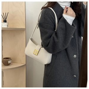 Close-up of minimalist cream leather underarm bag with gold geometric metal hardware