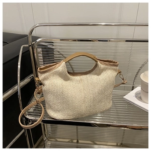 Détail du sac cabas en paille tressée avec poignées en cuir marron et texture beige