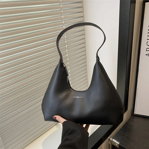 Minimalist black leather hobo bag with silver logo shown in an artistic setting