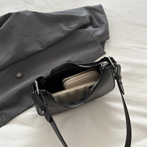 Interior view of black shoulder bag showing storage space for a wallet and phone