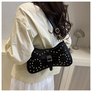 Détail du sac à bandoulière en cuir noir gaufré croco avec rivets dorés brillants