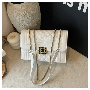 Detail of white quilted crossbody bag featuring a square black gem buckle and gold chain