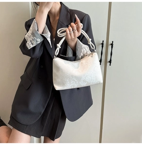Detail view of white snakeskin texture on a minimalist shoulder bag with elegant streamline