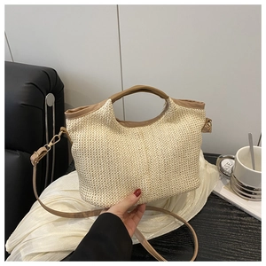 Détail du sac cabas en paille tressée beige avec poignées en cuir marron et bandoulière