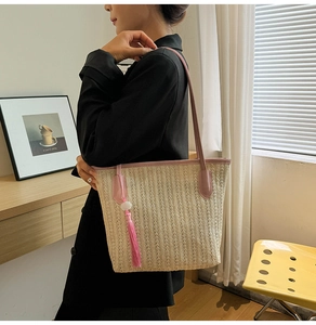 Detail of woven straw tote bag with pink leather trim and fringe tassel accessory