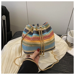 Detail of colorful woven straw bucket bag with gold chain strap and pearl drawstrings