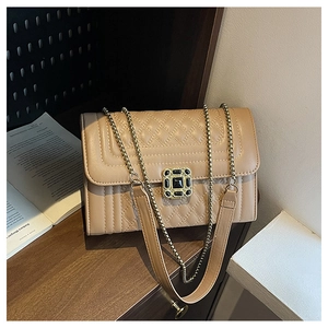 Detail of light brown quilted crossbody bag with stylish gem buckle on a wooden shelf