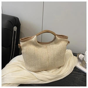 Détail de la texture en paille tressée et anses en cuir marron d'un sac cabas de plage
