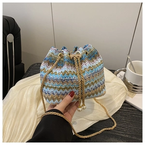 Detail of colorful woven bucket bag with gold chain strap and pearl drawstring closure