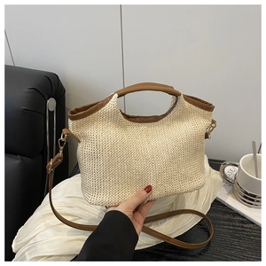 Détail du sac cabas en paille tissée avec poignées en cuir marron et bandoulière réglable