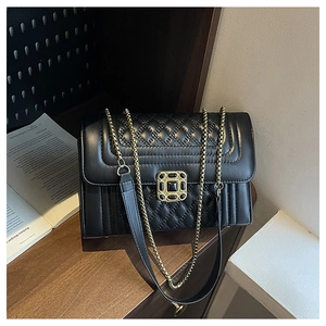 Detail of black quilted crossbody bag with golden vintage square buckle and chain strap