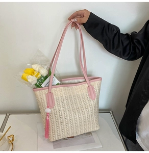 Detail of summer straw tote bag with pink leather handles and matching tassel charm