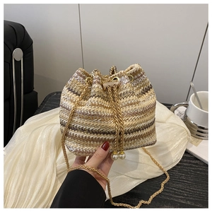 Detail of woven bucket bag featuring striped texture, metal chain and pearl accents