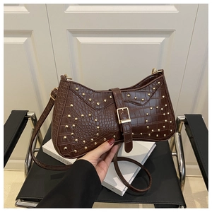 Détail du sac à bandoulière marron effet crocodile avec rivets dorés et boucle en cuir