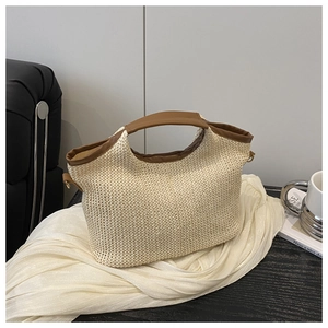 Détail du sac cabas en paille tissée avec anses en cuir marron et boucles métalliques