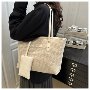 Detail of a beige woven tote bag with white leather straps and fashion logo tag