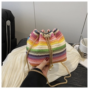 Detail of a colorful rainbow woven bucket bag with gold chain and pearl drawstring charms