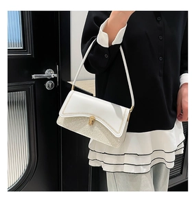 Detail of white leather shoulder bag with glitter finish and golden twist lock