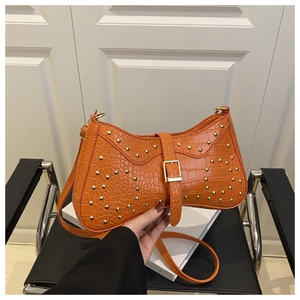 Détail du sac croissant orange avec texture crocodile et rivets dorés décoratifs