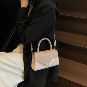 Elegant cream crossbody bag with glitter finish and V-shaped metal trim on steps