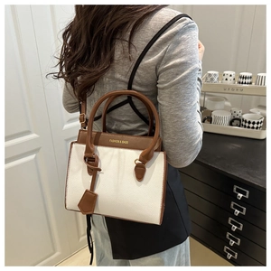 Detail of color-block tote bag with white and brown panels and fashion lettering