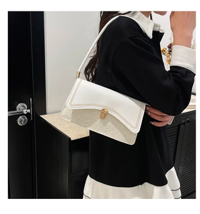 Detail of white shoulder bag featuring silver sequins and gold rectangular clasp closure