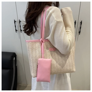 Detail of straw tote bag with pink leather trim and a small matching side pouch