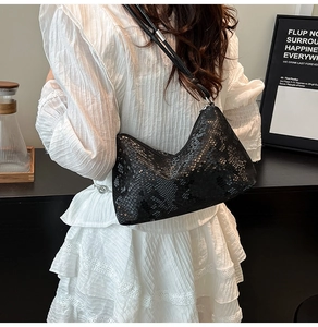 Detail showing the glossy black snake skin texture and silver buckle on the shoulder bag