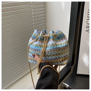 Detail of woven bucket bag with colorful wave patterns and elegant pearl charm