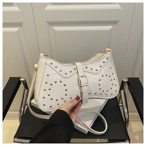 Détail du sac croissant blanc montrant la texture crocodile et les rivets dorés