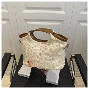 Détail du sac cabas en paille tressée avec poignées en similicuir brun et anneaux en D