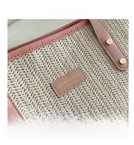 Detail of woven straw tote bag with pink leather trim and golden metal rivet studs
