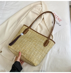 Detail of straw woven tote with leather handle, decorative tassel, and jade bead accent