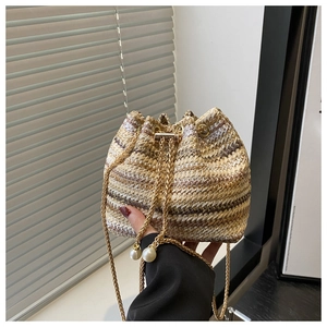 Close-up of woven bucket bag with pearl drawstring and golden chain strap details