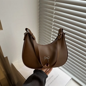 Dark brown leather crescent hobo bag with a silver bow accent and adjustable strap