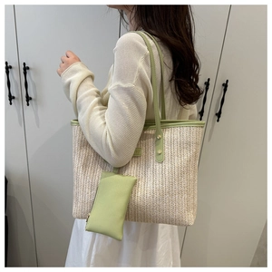 Detail of green straw tote bag showing woven texture and matching small pouch bag
