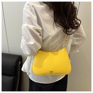 Detailed close-up of the bright yellow leather bag texture and metallic brand logo