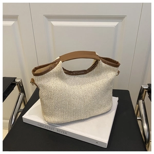 Détail du sac cabas tissé main montrant la paille beige et l'anse en cuir marron