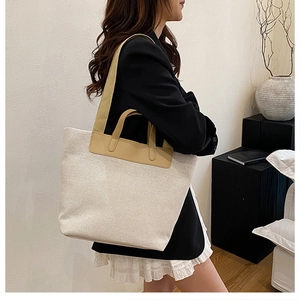 Close-up of minimalist canvas tote with premium brown leather trim and dual straps